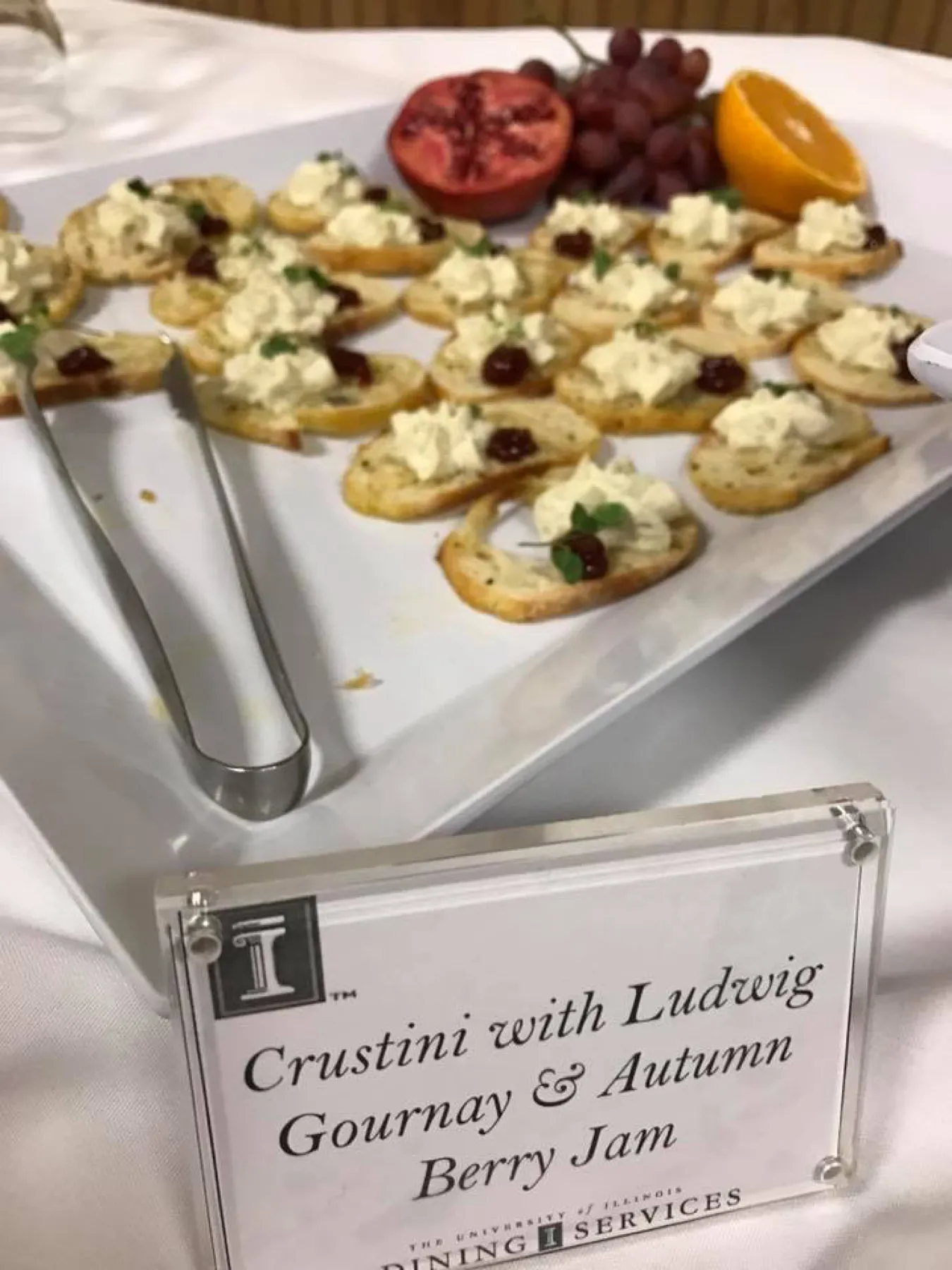 A platter of crostini with a card reading Crostini with Ludwig Gournay and Autumn Berry Jam.