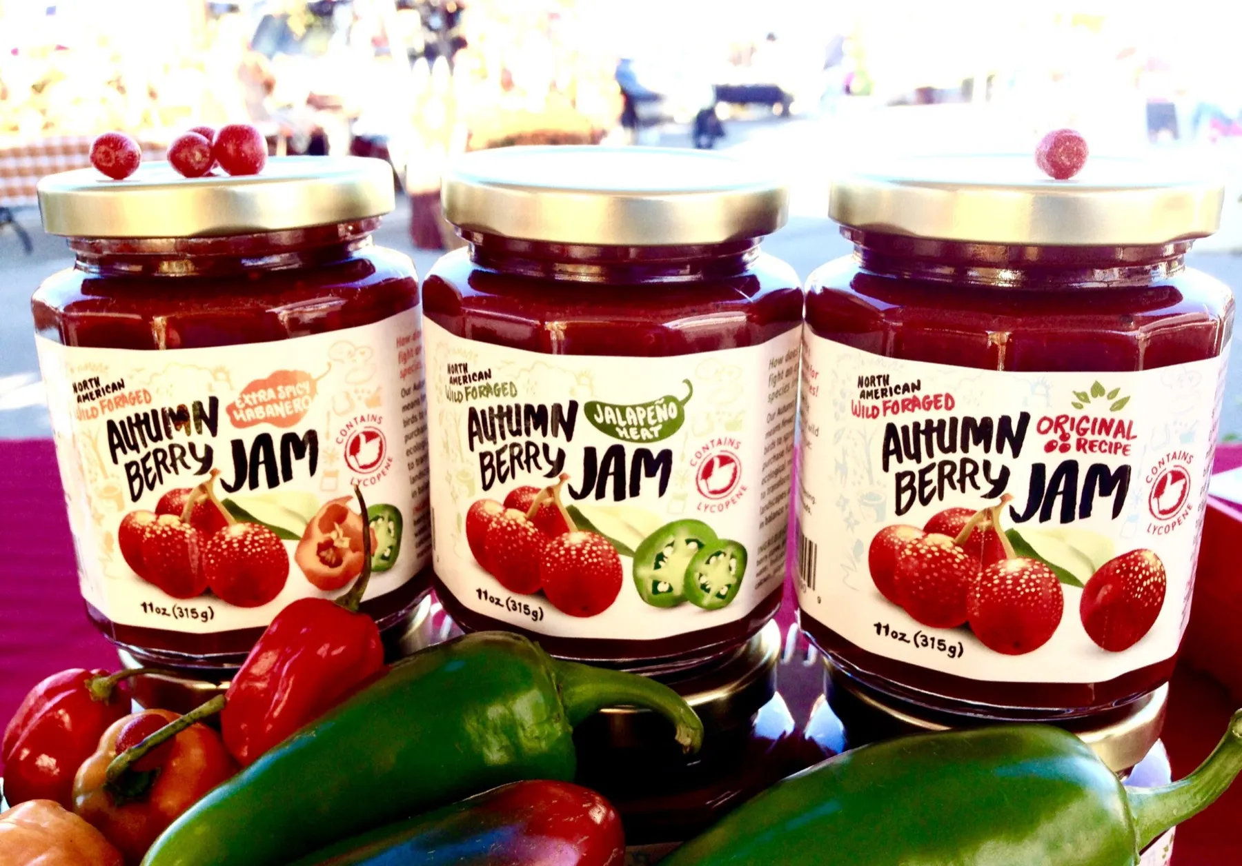 Three jars of Autumn Berry Jam, original, jalapeño and habanero, with fresh peppers.