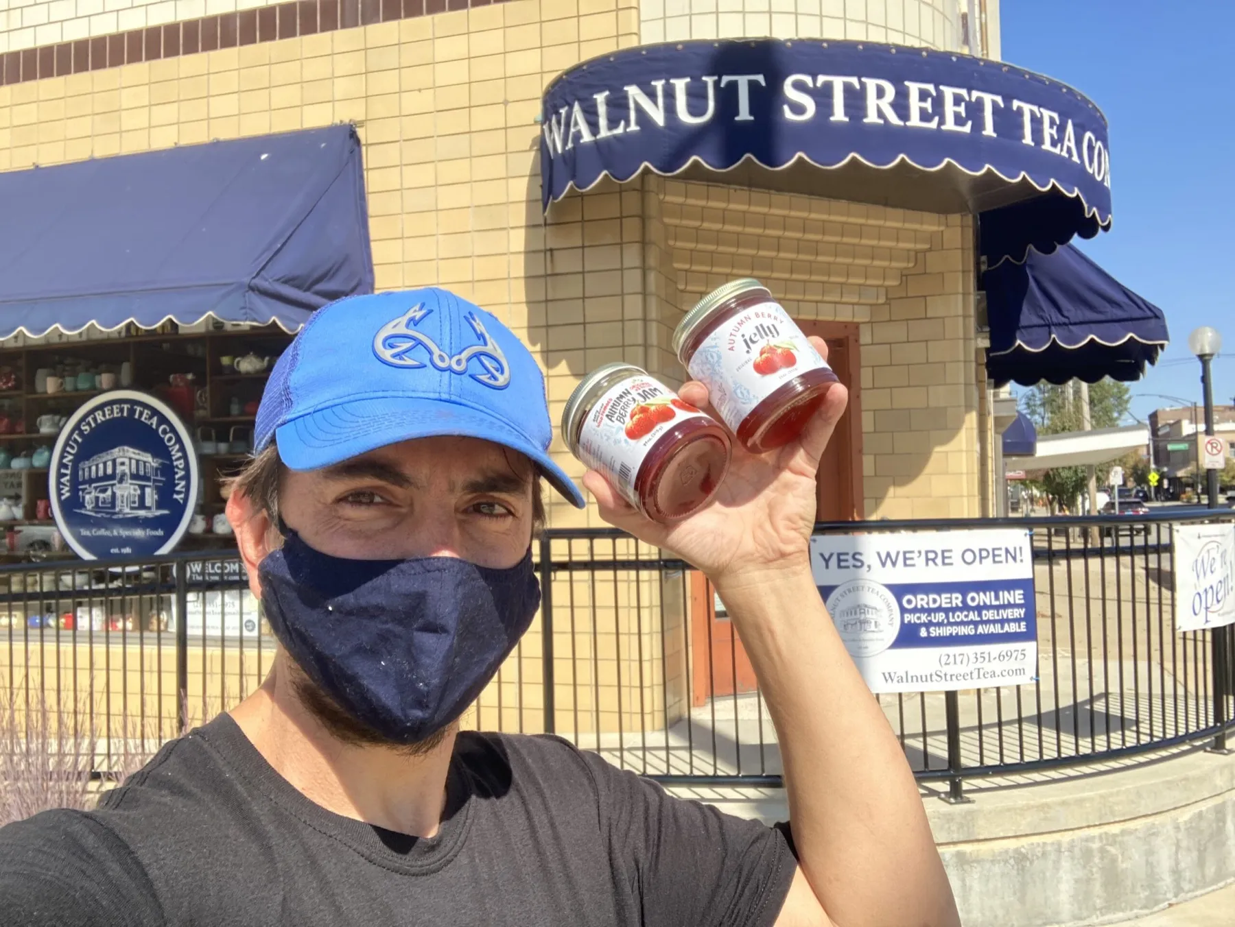 Dustin Kelly in a face mask holding two jars outside Walnut Street Tea Company.